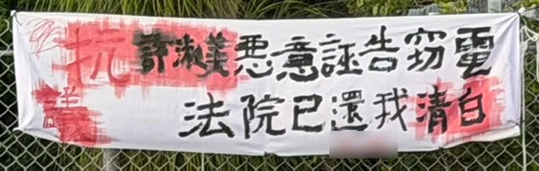 一張白布條,寫著「許淑美惡意誣告竊電 法院已還我清白」