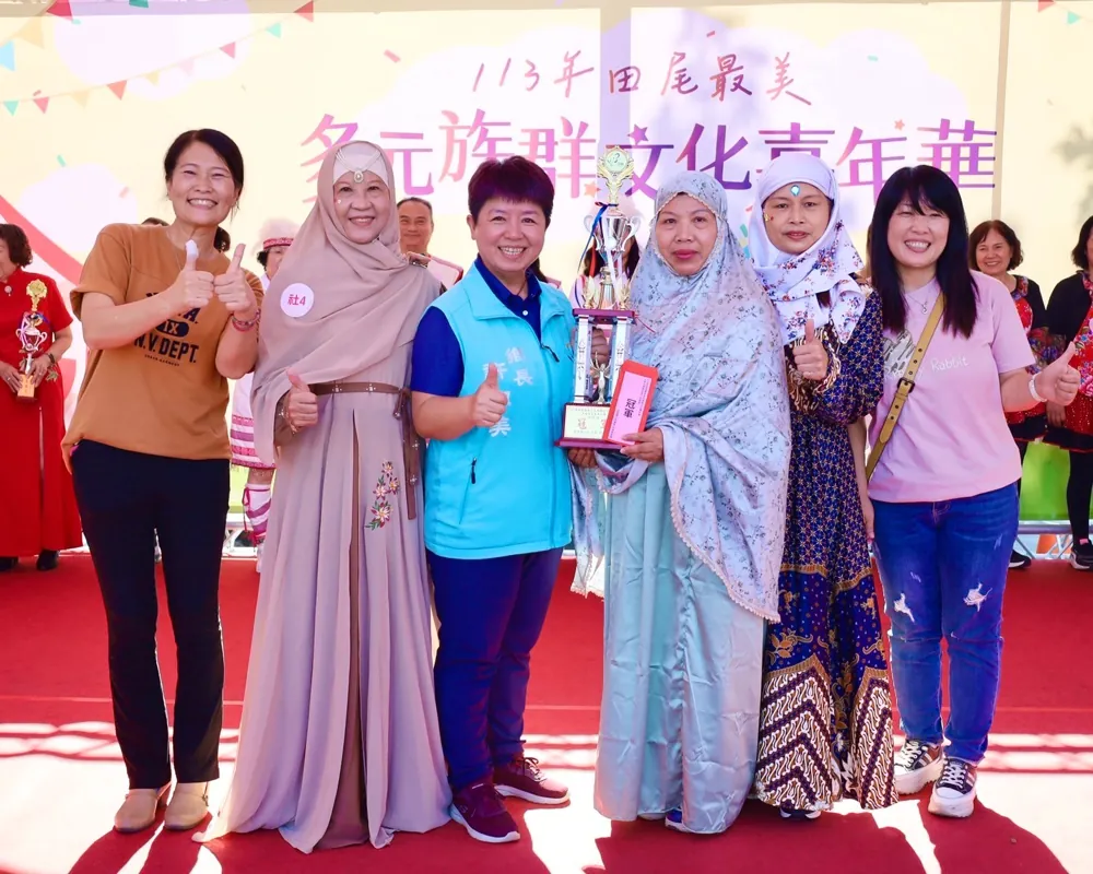 穿著傳統服飾的新住民姐妹與工作人員,手捧獎盃合影
