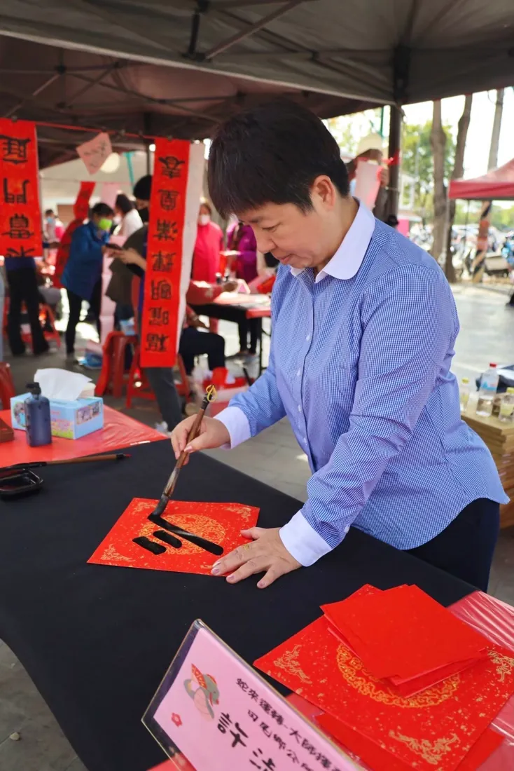 桌上攤開紅紙,有人提筆寫春聯
