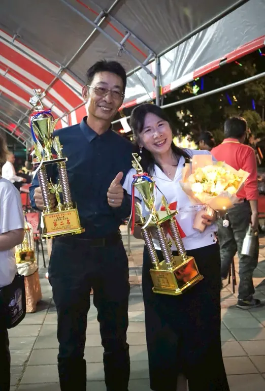 一對得獎的男女各捧著獎盃,笑著比讚