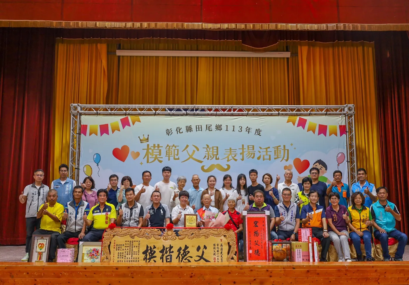「113 年度模範父親表揚活動」背板前,受表揚的父親與家人、來賓合影,前方擺著「模楷德父」匾額